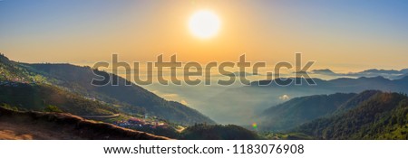 Beautiful panoramic landscape above clouds and mountains with sun rising in the middle.