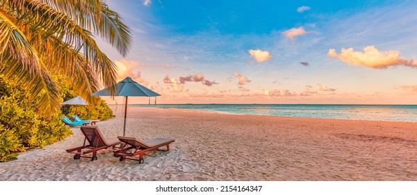 Beautiful panoramic nature. Tropical beach sunset as summer island landscape with chairs umbrella palm leaves calm sea shore, coast. Luxury travel panoramic destination banner for vacation or holiday - Shutterstock ID 2154164347