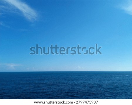 Beautiful panoramic view of the deep blue ocean meeting a clear blue sky at the horizon line during a bright sunny day.
