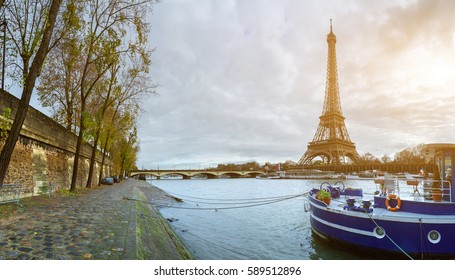 Beautiful panoramic view of the Eiffel Tower and Jena bridge from the river Seine embankment. Dramatic cloudscape. Traditional citycape in backlit morning sunbeam. Paris, France. 