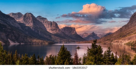 Beautiful Panoramic View of a Glacier Lake with American Rocky Mountain Landscape in the background. Dramatic Colorful Sunrise Sky. Taken in Glacier National Park, Montana, United States.