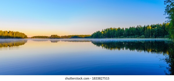 Beautiful panoramic view of Lake Haukivesi during sunrise. Light fog over the water. Specular reflection in the water. Saimaa lake system,  Rantasalmi, Savo, Finland. - Powered by Shutterstock