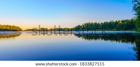 Beautiful panoramic view of Lake Haukivesi during sunrise. Light fog over the water. Specular reflection in the water. Saimaa lake system,  Rantasalmi, Savo, Finland.