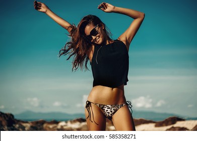 Beautiful Party Girl Dancing And Waving Hands On The Beach Over Blue Sky