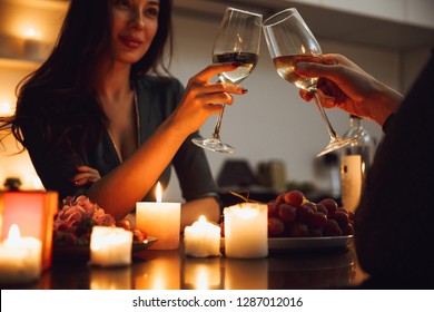 Beautiful passionate couple having a romantic candlelight dinner at home, drinking wine, toasting