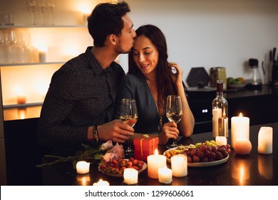 Beautiful passionate couple having a romantic candlelight dinner at home, kissing