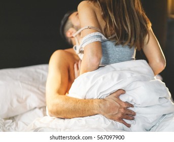 Beautiful passionate young couple having sex on the bed at home - Intimate and sensual moments of a couple making love in the bedroom - Vintage filter - Focus on the male hand