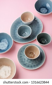 Beautiful pastel colours, blue, grey, beige dinnerware, plates bowls on pink table, top view, selective focus