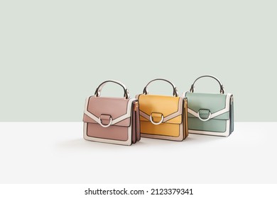 Beautiful pastel leather female fashion handbags isolated on light green background, perspective view