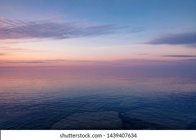 A beautiful pastel sunset over Lake Ontario. The sky reflects purple, blue and orange colors in the water. - Powered by Shutterstock