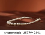 Beautiful pearl necklace on brown silk, closeup