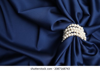 Beautiful pearls with dark blue silk as background, space for text