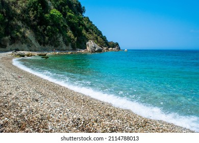 Beautiful pebble beach of Himare town at foot of mountains. Adriatic sea. Albania. Summer cloud landscape. Concept of summer holidays and relaxation.