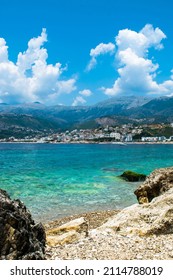 Beautiful pebble beach of Himare town at foot of mountains. Adriatic sea. Albania. Summer cloud landscape. Concept of summer holidays and relaxation.
