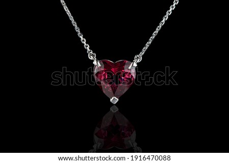 beautiful pendant with garnet with a gold chain on a black background close-up