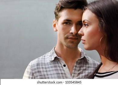 Beautiful Pensive Man And Woman Stand Near Gray Wall; Focus On Woman