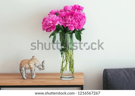 Beautiful peonies in the vase standing in the living room. Interior in details.