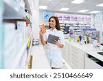 Beautiful pharmacist working and standing in a drug store and doing a stock take. Portrait of a positive healthcare worker or a chemist at his work.