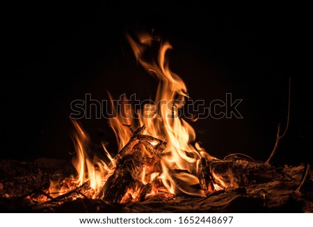 Beautiful photo of isolated bonfire with fierce flames of yellow and orange color depicting incomplete combustion of firewood, set on fire during the winter nights to keep the surroundings warm.
