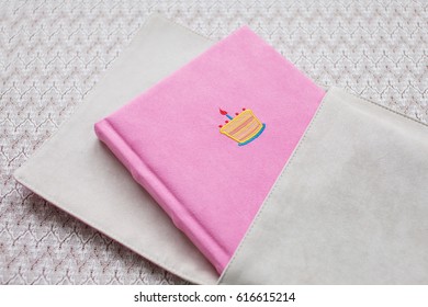 Beautiful Photobook In Light Pink Textile Cover With Textile Box. Baby Photobook With Decorative Embroidery Of Birthday Cake.   Low Depth Of Sharpness