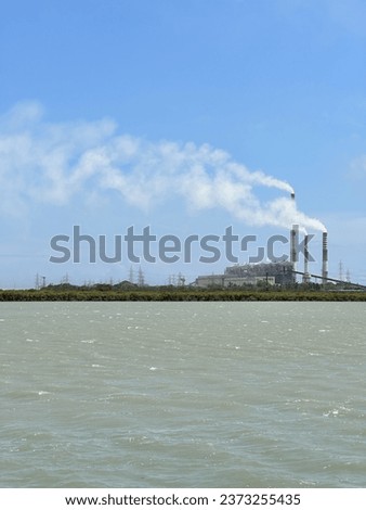 beautiful photograph of thermal nuclear power station industry air pollution white smoke chimney boilers blue sky sea ocean waves offshore powerplants green energy negative space india coastal town 