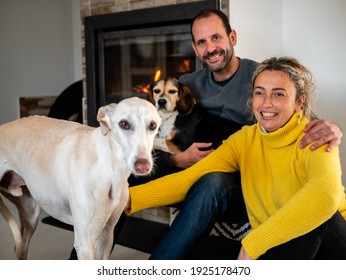 Beautiful Picture Of A Couple With Their Two Dogs, Beagle And Greyhound, Next To The Chimney Of Their House.