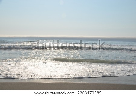 Beautiful picture of the tide, sand and waves coming and going as the sun is setting.  Reflection of light on the water and the sand cause the sand and to glisten and the water to sparkle.