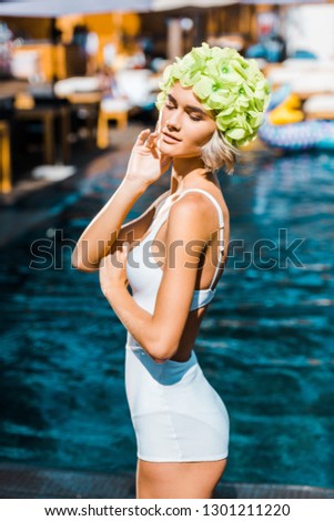 beautiful pin up girl posing in white swimsuit at poolside
