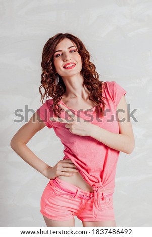 Beautiful pin up woman in pink shows two fingers