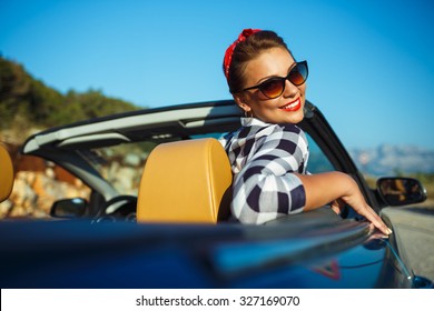 Beautiful pin up woman sitting in cabriolet, enjoying trip on luxury modern car with open roof, fashionable lifestyle concept