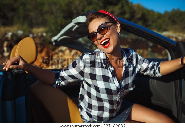 Beautiful pin up woman sitting in cabriolet,\
enjoying trip on luxury modern car with open roof, fashionable\
lifestyle concept
