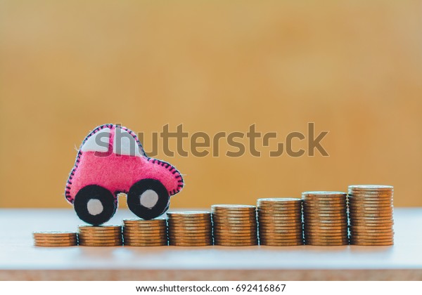 Beautiful\
pink car model driving on the stack gold coins with growing to\
money as collect interest, loan and saving for buy a new car and\
investment a chattel in the future\
concept.