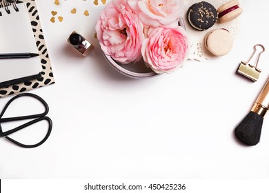 Beautiful pink flowers, french macarons, notepad and other cute feminine stuff on white background, top view
