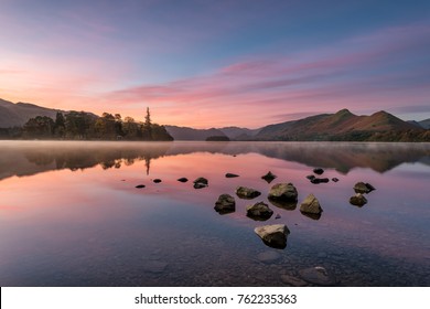 Beautiful Pink And Purple Pre Dawn Sunrise Sunrise With Mirrored Reflections In Lake. Taken At Derwentwater In The English Lake District.