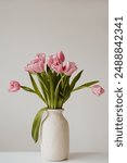 Beautiful pink tulip flowers bouquet in ceramic vase on white table. Aesthetic minimalist style floral composition with copy space