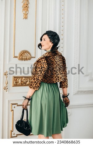beautiful and playful brunette in retro clothes, gloves, beret and with a handbag. the concept of the stylist's work. thematic photo shoot.