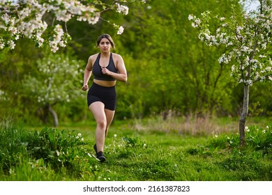 Beautiful Plus Size Runner Indian Woman Running On The Grass In The Orchard