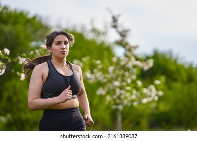 Beautiful Plus Size Runner Indian Woman Running On The Grass In The Orchard