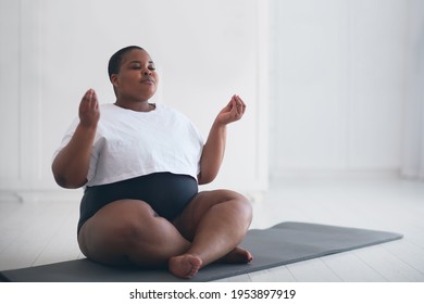 schöne und größer werdende Frau, die zu Hause Yoga-Übungen macht