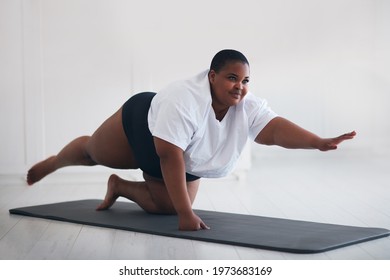 Beautiful Plus Size Woman Exercising On Sport Mat At Home, Lifting Legs And Arms Up