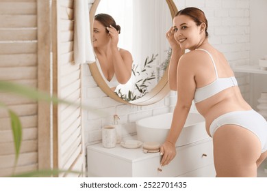 Beautiful plus size woman near mirror in bathroom - Powered by Shutterstock