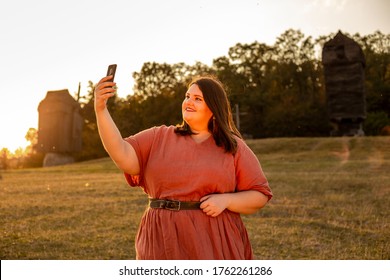 Beautiful Plus Size Woman In Red Dress Making Selfie Outdoors In The Sunset Light