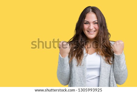 Beautiful plus size young woman wearing winter jacket over isolated background celebrating surprised and amazed for success with arms raised and open eyes. Winner concept.