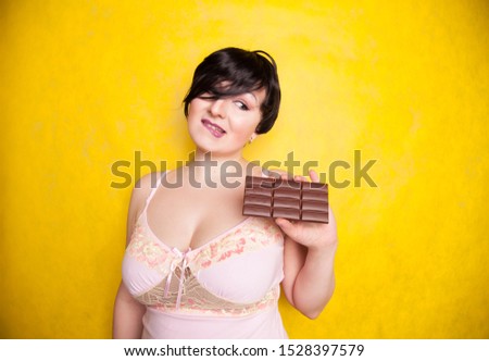A beautiful plus-size woman flirts with taking a bite of dark chocolate.