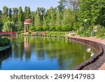 Beautiful pond in the park Kharkiv city, Ukraine. Picturesque landscape of the shore with a gazebo and garden design on a summer sunny day