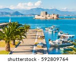 Beautiful port of Nafplio city in Greece with small boats, palm trees and Bourtzi castle on the water with selective focus