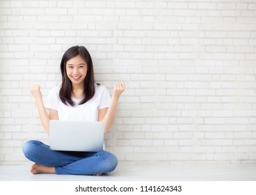 Beautiful of portrait asian young woman excited and glad of success with laptop computer, girl sitting working on cement brick background, career freelance business concept.