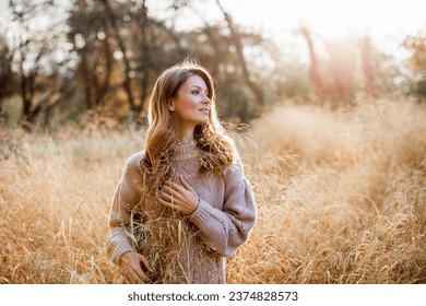 Стоковая фотография: Beautiful portrait of a Caucasian girl in an autumn coat walks on a warm sunny day in the autumn park. Happy young woman enjoying golden autumn