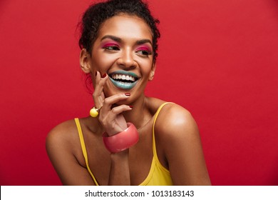 Beautiful Portrait Of Happy African American Female Model In Yellow Shirt Smiling And Posing On Camera Isolated Over Red Background