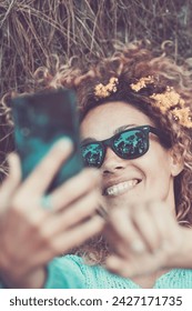 Beautiful portrait of happy cheerful caucasian woman do selfie picture with modern phone - brown leaf and anture around his head and on his hair - enjoy nature and forest concept